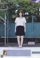 A woman in a school uniform standing in front of a fence.