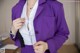 A woman in a purple suit is adjusting her tie.