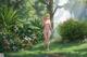 A woman in a bikini walking through a lush green forest.