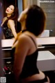 A woman in a black lingerie looking at herself in the mirror.