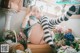 A woman sitting on top of a dresser next to flowers.