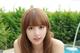 A woman with long brown hair and bangs posing by a pool.