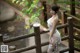 A woman in a white dress standing on a wooden bridge.