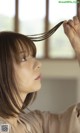 A woman holding her hair in front of a window.