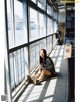 A woman sitting on the ground in front of a window.