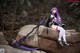 A woman sitting on top of a rock holding a sword.