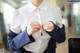 A woman in a white shirt and blue jacket adjusting her tie.