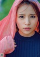 A young girl wearing a pink veil over her head.