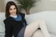 A woman in a school uniform is sitting on a bed.