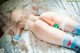 A woman laying on a bed with a carrot in her butt.