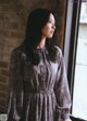 A woman standing by a window looking out the window.