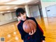 A young woman holding a basketball on a basketball court.