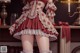 A woman in a red and white dress standing next to a lamp.